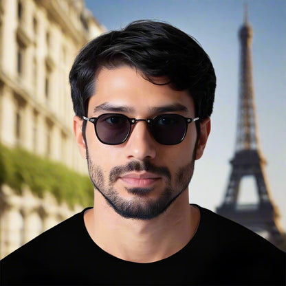 Man wearing dark sunglasses and a black shirt against a plain background